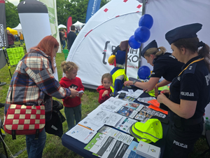 policjantki na stoisku profilaktycznym a przed nimi dzieci i rodzice