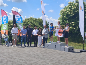 podium na nim stoją dzieci obok osoby wręczające nagrody