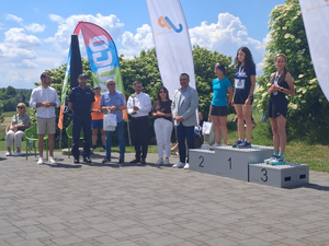 zwycięzcy stojący na podium obok osoby wręczające nagrody