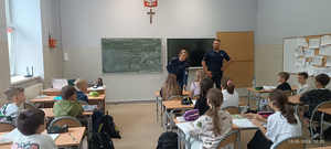 policjanci w mundurach w sali lekcyjnej przed nimi siedzą uczniowie