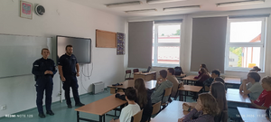 policjanci w mundurach w sali lekcyjnej przed nimi siedzą uczniowie w ławkach