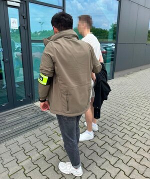 policjant prowadzi zatrzymanego do komendy
