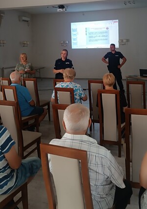 policjanci w sali podczas prelekcji przed nimi siedzą seniorzy