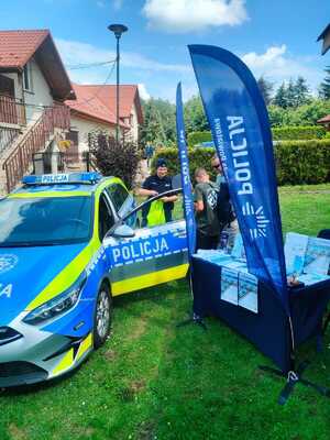 radiowóz policyjny obok policjantka i odwiedzający stoisko