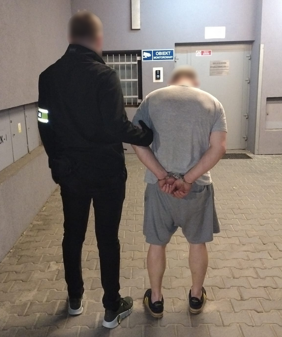 policjant prowadzi zatrzymanego do izby zatrzymań