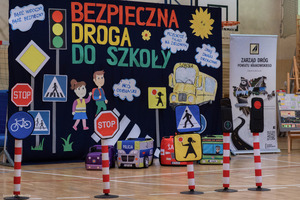 duży plakat z napisem bezpieczna droga do szkoły i małe znaki drogowe