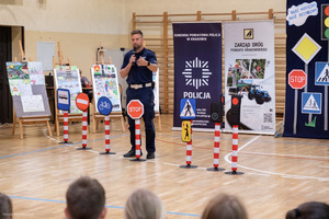 policjant pokazuje dzieciom znaki drogowe