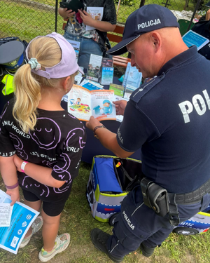 policjant przekazuje dziewczynce ulotkę edukacyjną