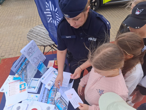 policjantka wręcza dzieciom ulotki