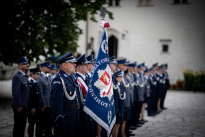 policjanci stojący w szeregu, sztandar komendy powiatowej policji w Krakowie na pierwszym planie
