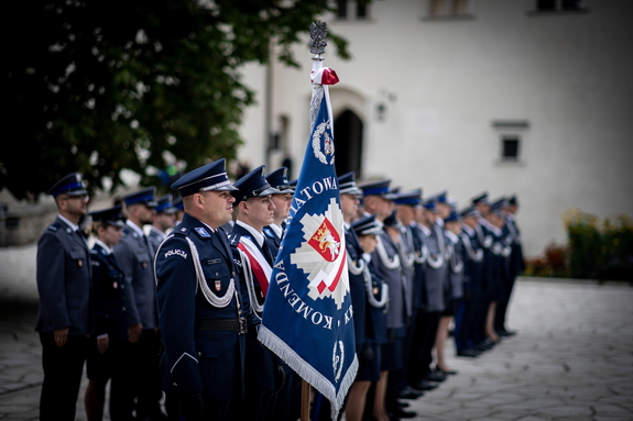 policjanci stojący w szeregu, sztandar komendy powiatowej policji w Krakowie na pierwszym planie