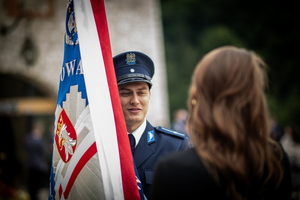 policjant w mundurze stojący ze sztandarem naprzeciwko kobiety
