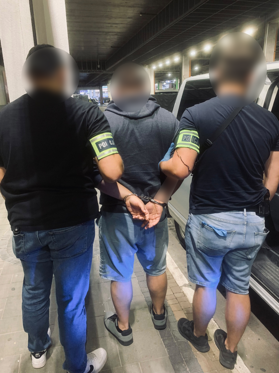 dwóch policjantów nieumundurowanych prowadzi zatrzymanego mężczyznę