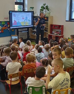 policjantka w mundurze podczas prelekcji przed nią siedzą dzieci