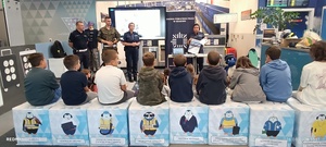 funkcjonariusze prowadzący prelekcję przed nimi siedzą uczestnicy półkolonii