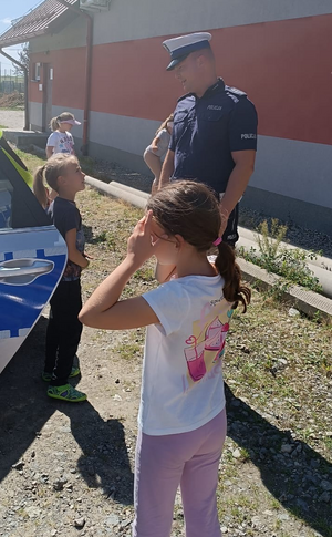 policjant pokazuje dzieciom oznakowany radiowóz