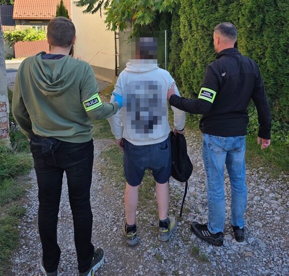 policjant bez munduru i strażnik graniczny bez munduru z opaskami na rękach "policja" i "straż graniczna" prowadzą zatrzymanego mężczyznę