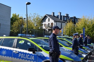 oznakowane radiowozy policyjne obok nich stoją umundurowani policjanci