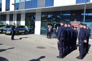 policjanci i goście stoja przed budynkiem komendy podczas uroczystości