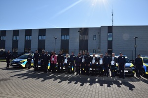 zdjęcie grupowe policjantów i zaproszonych gości za nimi radiowozy