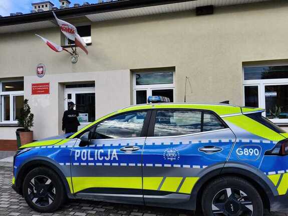 oznakowany radiowóz przed budynkiem szkoły