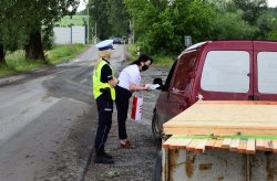 policjantka i pracownica PKP wręczające kierowcy ulotkę, w tle przejaz kolejowy