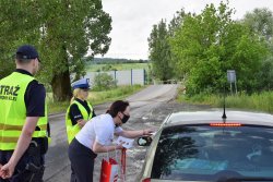 policjantka i pracownicy PKP podczas wręczania kierowcy ulotki, w tle przejaz kolejowy