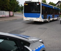 jadący autobus i widoczny bok radiowozu jadący za autobusem