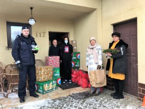 stojacy przed domem dziecka komendant komisariatu, dwie kobiety i męzczyzna z chłopakiem, obok leżące na ziemi prezenty