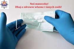 dłonie z załozonymi rękawicami trzymajace maseczke ochronną z napisem noś maseczkę dbaj o zdrowie własne i innych osób, w lewym górnym rogu znajduje się logo KPP w Krakowie