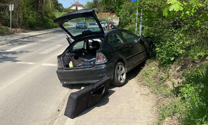 rozbite na słupie BMW, widoczne od tyłu, z otwartym bagażnikiem, przed nim radiowóz, obok którego stoi policjant