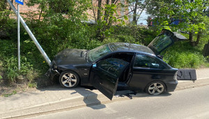 rozbite na słupie BMW, widoczne z boku, drzwi od kierowcy otwarte, bagażnik otwarty, słup przechylony