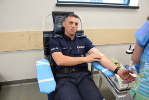 umundurowany policjant podczas oddawania krwi na fotelu