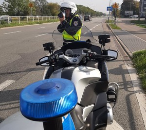 policyjny motocykl obok policjant prowadzący pomiar prędkości