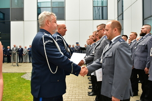 zastępca komendanta wojewódzkiego podający rękę awansowanemu policjantowi w szeregu