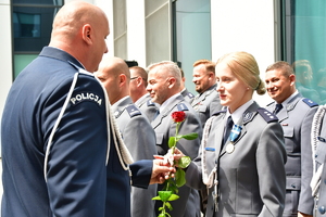 komendant powiatowy wręczający róże policjantce stojącej w szeregu