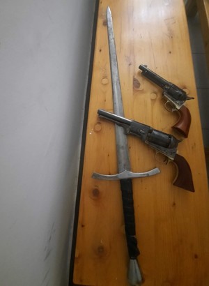 dwa pistolety i miecz leżące na biurku (1)