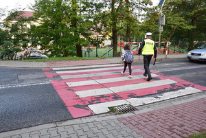 policjant przeprowadzający dziewczynkę przez pasy