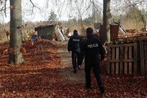 dwaj policjanci przemieszczajacy się parkiem gdzie zamieszkują bezdomni