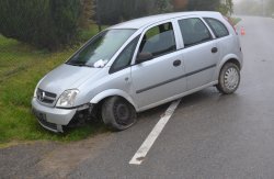 samochód w połowie w rowie, w połowie na drodze, z przebitą przednią oponą