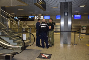 policjant, strażnik graniczny, pracownik SOL  stojący przy strefie bagażowej na lotnisku
