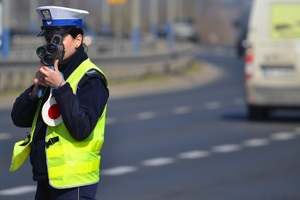 policjant ruchu drogowego mierzący fotoradarem do pojazdów przy drodze