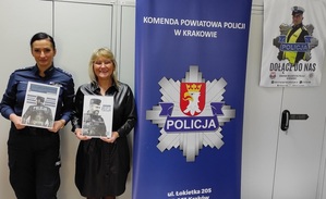 policjantka obok kierowniczka filii Urzędu Pracy, trzymajace w rękach plakaty wstąp do Policji, obok nich banek KPP Krakóbanerze KPP Kraków, na stanowisku w Urzędzie Pracy, obok niej pracownicy UP (2)