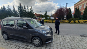 policjanci kontrolują pojazd, obok uczniowie wręczają ulotki kierowcy (2)