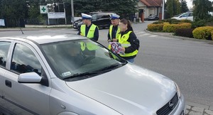 policjanci kontrolują pojazd, obok uczennica wręcza ulotki kierowcy (2)