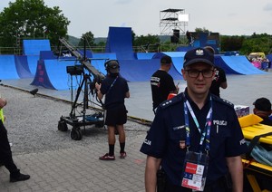 policjant stojący przodem w tle rampa i skaczący BMX