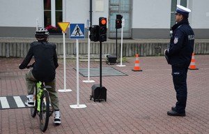 chłopak na rowerze zdający egzamin praktyczny na kartę rowerową, obok policjant