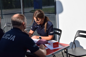 dwoje policjantów siedzących naprzeciwoko siebie podczas wypełniania ankiety