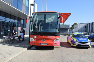 kwiobus widoczny przodem, obok radiowóz, z drugiej strony policjanci stojący przy krwqiobusie