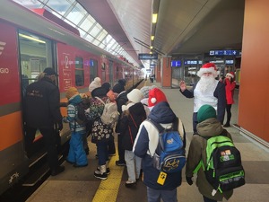 3. dzieci wchodzące do pociągu, obok stojący mikołaj, który im macha